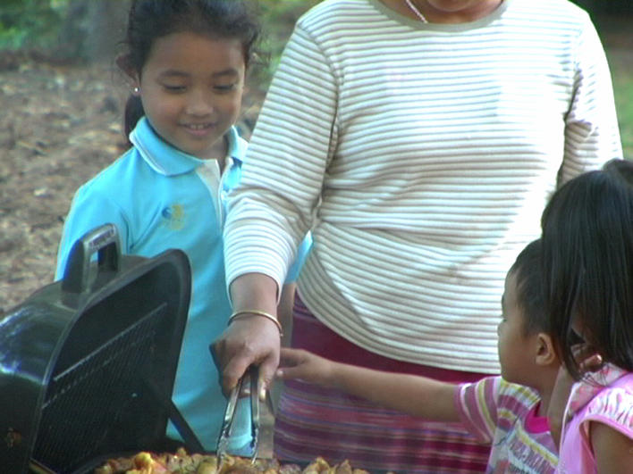 Woman and children grilling outside their home